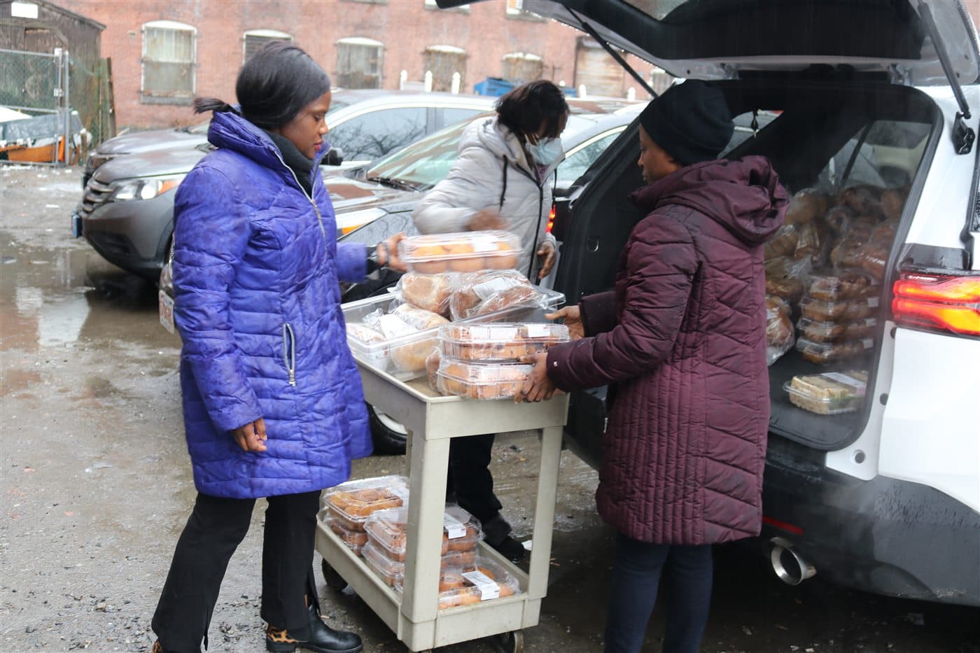 HESM volunteers unloading fresh food from the ministry vehicle onto a delivery cart during a winter outreach run in Boston