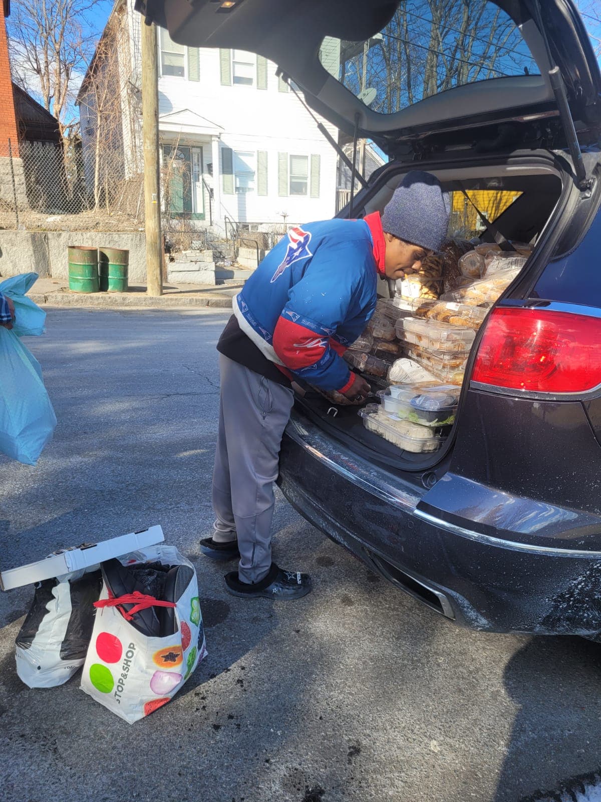 A volunteer loading prepared food into a vehicle for HESM outreach